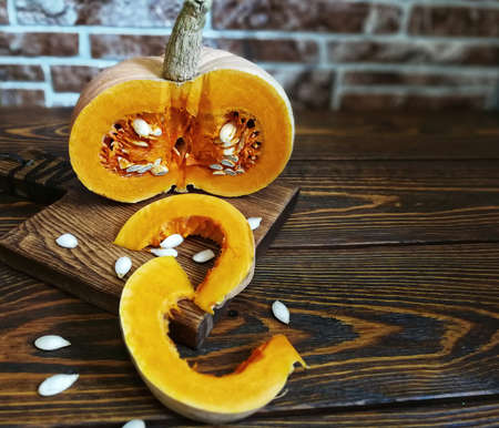 sliced pumpkin with a knife on a wooden Board and the old backgroundの写真素材