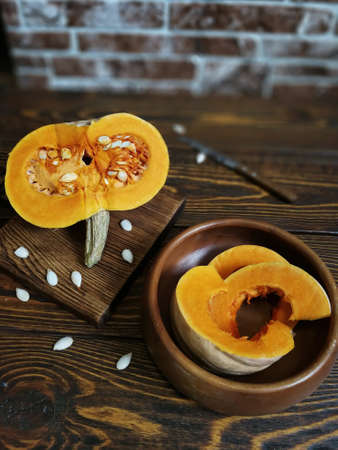 sliced pumpkin with a knife on a wooden Board and the old backgroundの写真素材