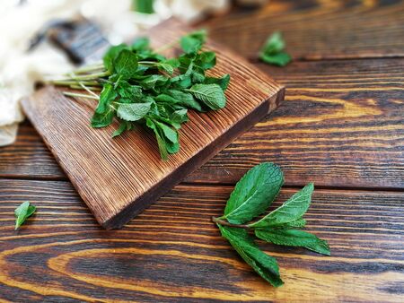 bunch of mint on brown wooden chopping Board on wooden backgroundの写真素材