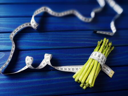 asparagus wrapped with measuring tape on blue wbackgroundの写真素材