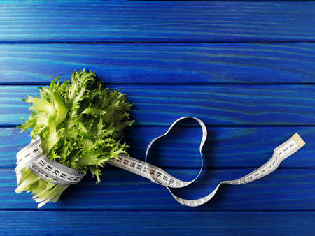 lettuce leaves wrapped with measuring tape on blue backgroundの写真素材