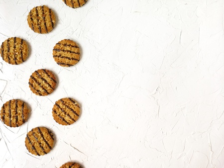 cookies poured with chocolate and peanut pieces lie on a light tableの写真素材