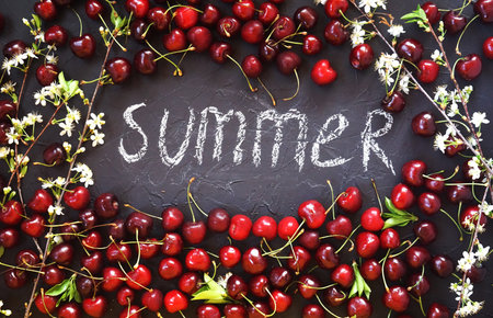 red and Burgundy cherry with flowering branches on a black textured background with water drops