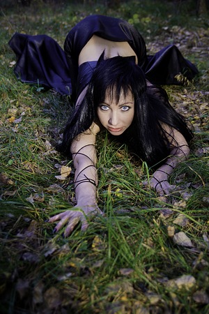 girl witch brunette in black leather top and long black skirt with long black hair in autumn forestの写真素材