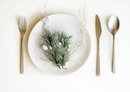Picture of Christmastime table setting, white festive plate with knife and fork, shiny silver...