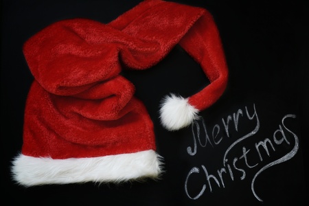 Christmas decoration with place for greeting on chalk blackboard, Santa Claus hat and gift boxesの写真素材