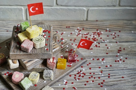 various national Oriental sweets, with paper flags of Turkey, Turkish delight on a wooden white brushed stand and on a white brushed background, horizontal, the concept of the independence day of Turkeyの写真素材