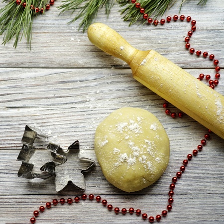 Christmas baking. Ginger dough for gingerbread, gingerbread men, stars, Christmas trees, rolling pin, flour. On the home kitchen white marble table. Copy space.の写真素材