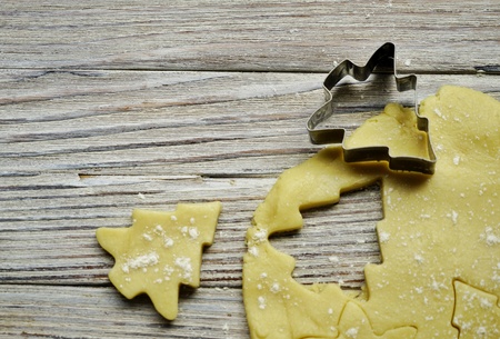 Christmas baking. Ginger dough for gingerbread, gingerbread men, stars, Christmas trees, rolling pin, flour. On the home kitchen white marble table. Copy space.の写真素材
