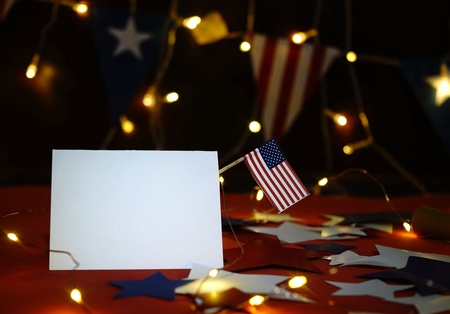 Fireworks display celebrates the independence Day of the United States of America nation on the fourth of July with the us flag , sparklers , candy, on the red background and on the background of Christmas garland and bokeh, with the stars , the end of the Celebration of freedom.の写真素材
