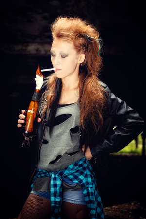 sexy woman model wearing a stylish trendy leather biker jacket and grunge hipster plaid shirt and ripped mesh pantyhose. fluffy blonde hair with Mohawk and smoky bright makeup. Fashion style of rock and roll.の写真素材