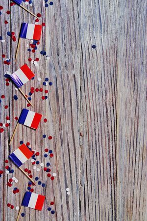 The national holiday of July 14 is a happy Independence Day of France, Bastille Day, the concept of patriotism, memory, place for text, confetti and flags on a wooden table, horizontalの写真素材