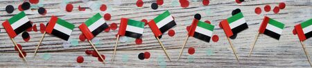December 2 is the independence day of the United Arab Emirates. happy day of patriotism, faith, freedom. Mini flags on wooden background with confettiの写真素材