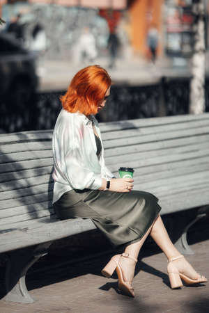 A red-haired woman in the city center, walking down the street. high quality photoの写真素材