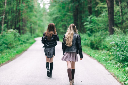 Two girls, blonde and brunette on the road in the summer forest. high quality photoの写真素材