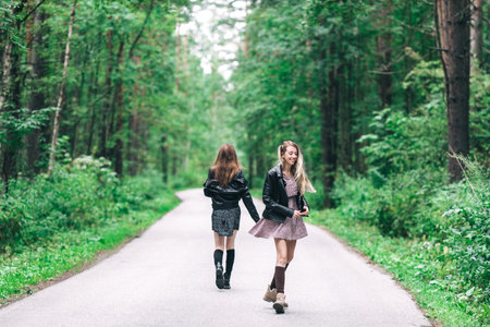 Two girls, blonde and brunette on the road in the summer forest. high quality photoの写真素材