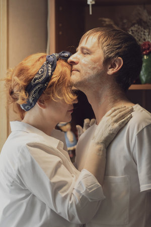 A couple in love in white shirts and jeans, a date in a pottery workshop, working together on one...