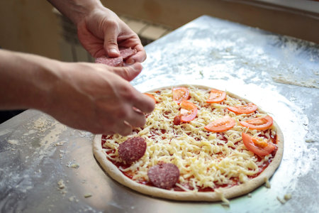 food cooking, culinary and people concept - cook or baker hand with pizza on peel at pizzeriaの写真素材