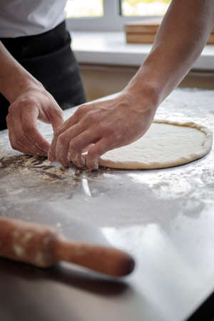 hands of the cook kneading pizza dough close-upの写真素材