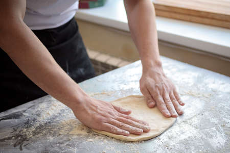 hands of the cook kneading pizza dough close-upの写真素材
