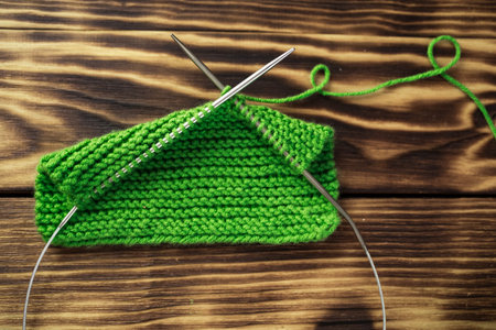 Started knitting on knitting needles, with yarn on a rustic wooden table, with green branches of a Christmas tree. We knit warm clothes with our own hands for cold winters and frosts during the crisisの写真素材
