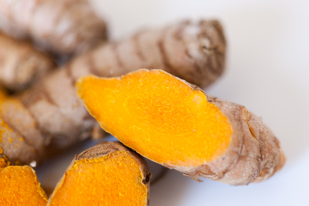 Turmeric roots macro with turmeric powder isolated on white backgroundの写真素材