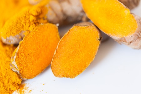 Turmeric roots macro with turmeric powder isolated on white backgroundの写真素材