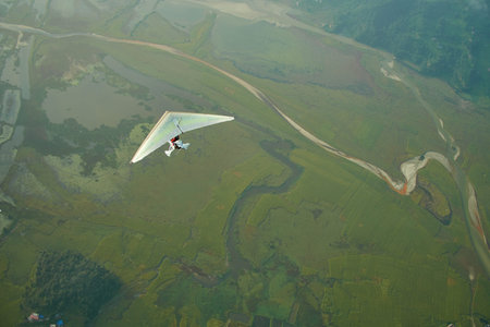 Ultralight aircraft and trees and snowcapped peak at background in the Himalaya mountains, Nepal