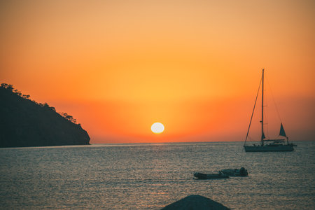 Orange sunset above sea with boat amazing Golden reflection of the sun on the calm waves. Summer landscape with sun and sea in Turkeyの写真素材