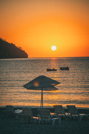 Orange sunset above sea with boat amazing Golden reflection of the sun on the calm waves. Summer landscape with sun and sea in Turkeyの写真素材