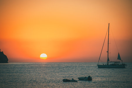 Orange sunset above sea with boat amazing Golden reflection of the sun on the calm waves. Summer landscape with sun and sea in Turkeyの写真素材