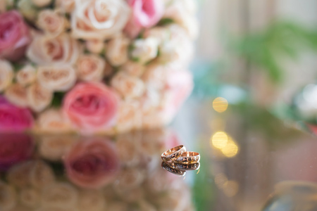 wedding rings on the table with a bouquetの写真素材