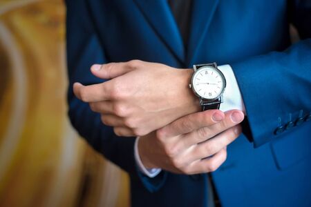 the man in the blue suit looks at his watch, straightens them, hands close upの写真素材