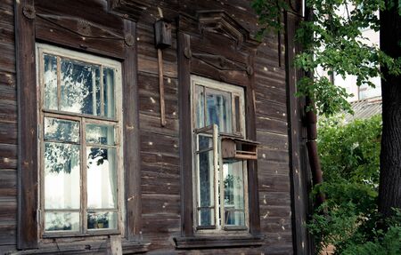 Old window with a bird feeder in an old wooden houseの写真素材