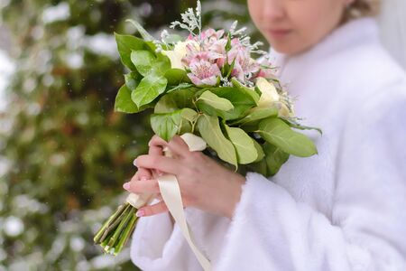 Delicate wedding bouquet in hands of bride in whiteの写真素材