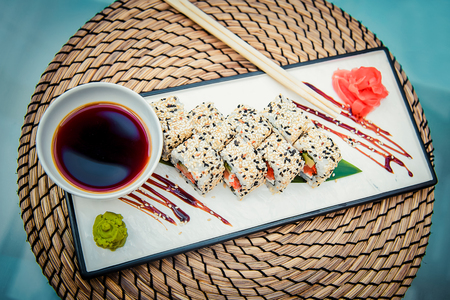 Rectangular plate with delicious rolls, soy sauce, ginger and wasabi on the tableの写真素材