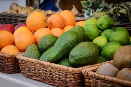 Bright green avocado and other fruits on the counter in a wicker trayの写真素材