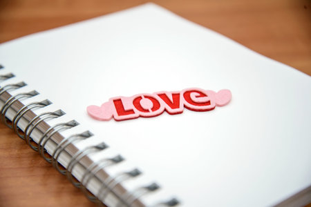 Open notebook with white pages and bright word Love