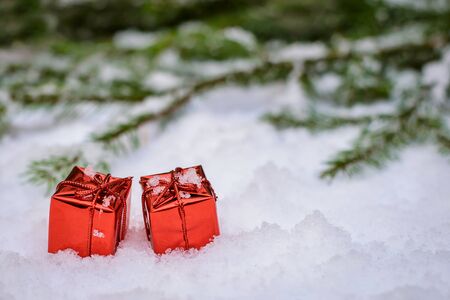 Two little red shiny boxes with Christmas gifts on the snow in winterの写真素材