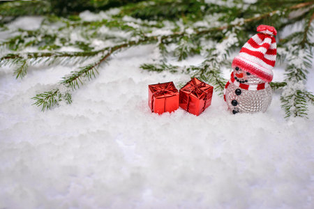 Christmas winter fairy-tale scene with a toy snowman in cap and scarf with best gifts in red boxes...