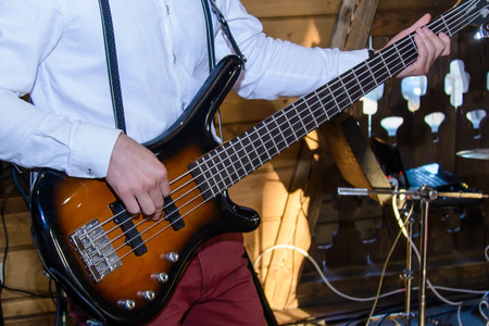 The musician in white shirt plays a brown guitar closeup
