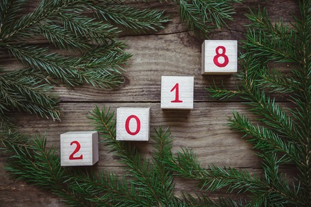 Beautiful picture with green Christmas tree branches and dices with the number 2018 on wooden background, top viewの写真素材