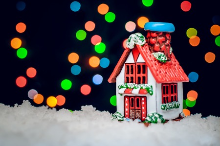 Christmas winter night is a picture with the house with the red roof on the background of colorful bokeh lightsの写真素材