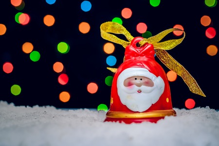 Large red Christmas bell with Santa drawn on the background of colorful bokeh lightsの写真素材