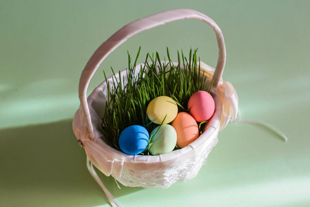 Beautiful bright picture with colored Easter eggs and grass in a white woven basket