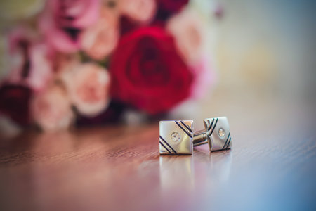 Beautiful cufflinks for sleeves on a wooden table next to the wedding bouquet
