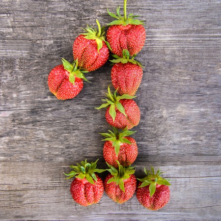 The number one 1 of the largest sweet tasty ripe red strawberries on wooden rustic backgroundの写真素材