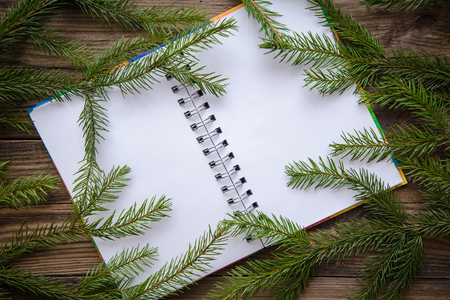 New year and Christmas festive picture with fir branches, and open notepad on a wooden rustic backgroundの写真素材