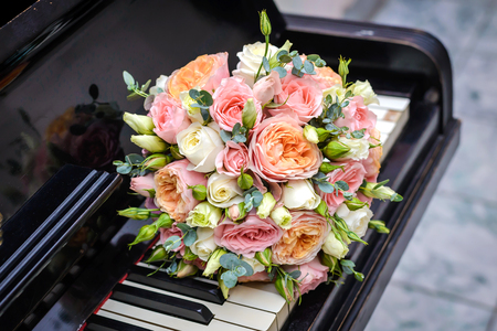 Beautiful wedding bouquet of pink and white roses is on the keyboard of the black pianoの写真素材