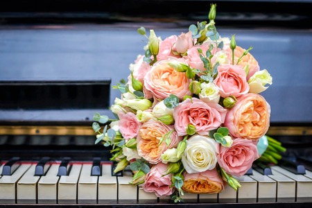 Beautiful wedding bouquet of pink and white roses is on the keyboard of the black pianoの写真素材